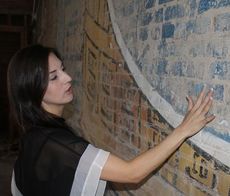 Jessica Monroe will open the Greer Trading Post at the Reece Building, where the Snowdrift sign was uncovered. She points to a place cleaned by water that shows the vibrant blue color when cleaned.
