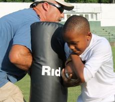 Knia Cook practices the technique of protecting the football while making contact. Coach Sonny Carter holds the hand dummy.
 
 