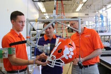 Alex Bina (left), Gregory Batt (center) and John Desjardins are using a linear drop tower with an anthropomorphic head model for their football helmet facemask tests.
 