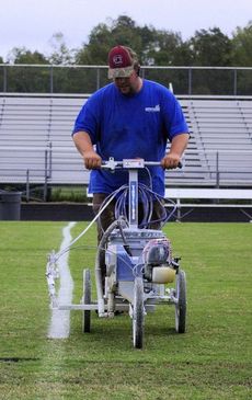 Donny Pittman lines the field at Blue Ridge High School. A team of volunteers spray paint and line the field Wednesday night for Friday home games.