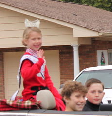 A young beauty queen braved the cold and rainy weather, smiling and waving, while traveling the parade route sitting on the back of a convertible.
 