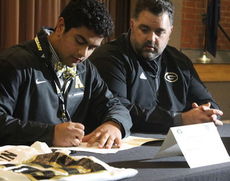 Noah Hannon officially signs with Appalachian State as his father, Chad, witnesses the event.
 
