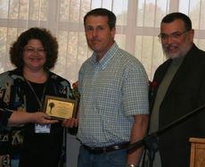 Jennie Thomas, left, area supervisor of the Bryant Center, and Alberto Delgado, right, Bryant Center job coach, present Dennis Kimbrell the Client of the Year award.