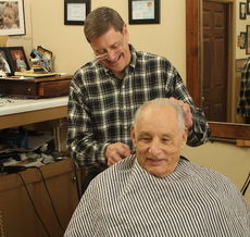 Mike Bullock is all smiles as he gives customer Wes McKenzie a trim Monday.
 