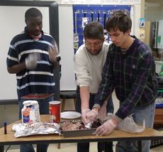 Washington Center students Cleveland Davis, left, and Paul Barnette, right, assisted by teacher McKenzie Riley, create baked treats as gifts for the school staff.