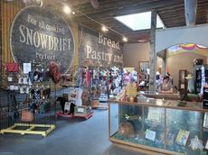 The panaromic view of The Trading Post shows the merhandise displayed with the Snowdrift signage on the left side of the shop. Jessica Monroe has brand merchandise displayed of Snowdrift dating to the early 1900s.