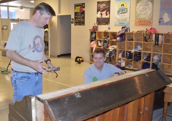 Jamie Dewberry and Andy Wettlin work on refurbishing a donated piano that will be used in Mary Poppins.
 