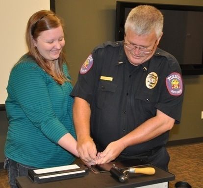 Greer Police Lt. Jim Holcombe rolls Madison Hinton's fingerprint today at CSI: Camp. Today's topics were learning the techniques of gathering fingerprints and visiting Greer Municipal Court with Judge Henry Mims presiding.