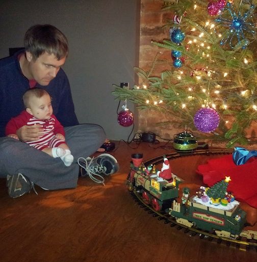 Scott and Tanner sitting near the Christmas tree watching our toy train go around and around.