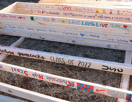 Students wrote encouraging messages on the beams of the wall, which will become part of the home during construction.
 