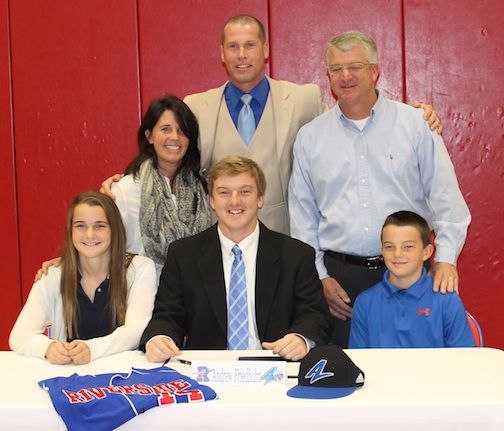 Baseball coach Travis Pitman joins Andrew Friedholm and his family during the signing ceremony.
 