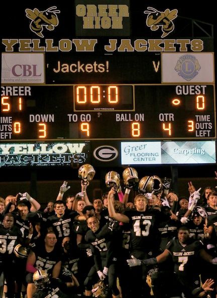 Greer players celebrate their perfect regular season in front of the scoreboard.
 