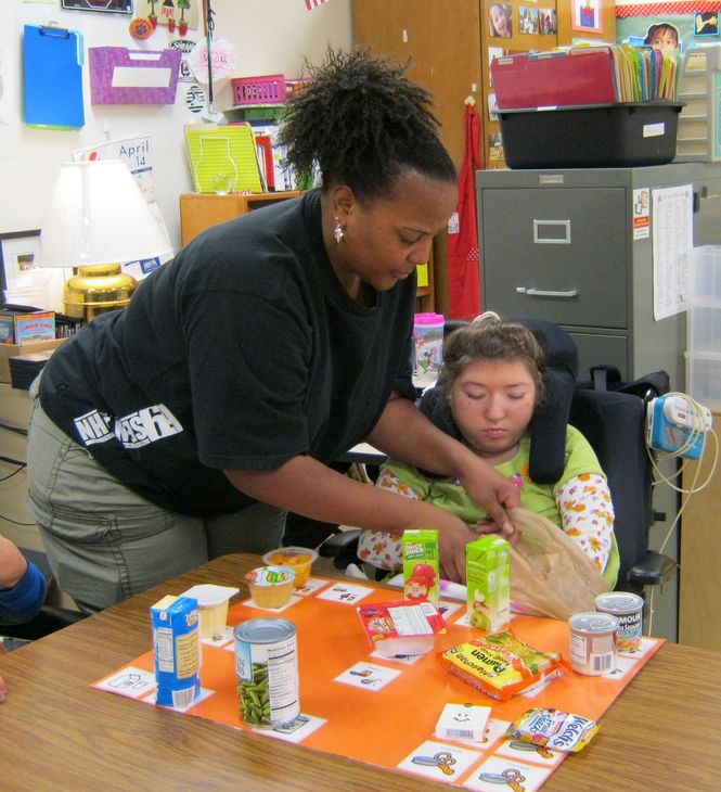 Washington Center student Victoria Johnson is assisted by Para-educator Maxine Wilkes assembling food bags for needy children.