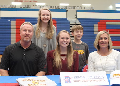 Kendall Claxton, is flanked by parents Craig and Sena while sister, Molly, and brother, Mitchell, are in the back during the signing ceremony.