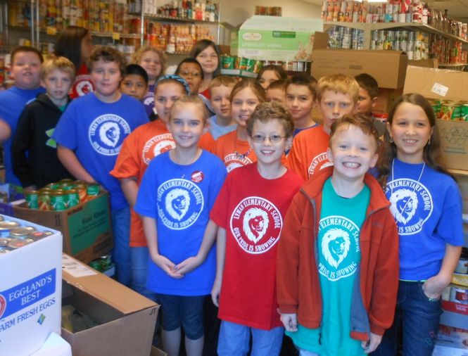 Fourth graders from Lyman Elementary School pose for a photo in GreerToday surrounded by 5,235 cans of food they collected for the Soup Kitchen. some of the stacks of food are taller than students.