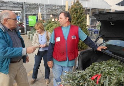 Rick Carroll of Lowe's places a Christmas tree in the trunk of the car belonging to Clinton and Lludmyla Patterson of Holly Springs.