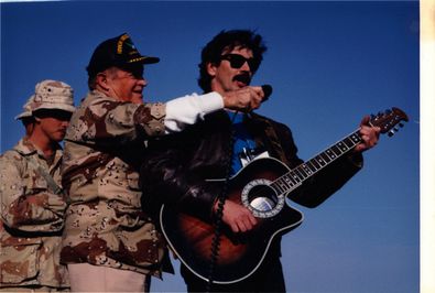 Bob Hope, the iconic entertainer who produced hundreds of shows overseas to perform for the troops, holds the microphone for Aaron Tippin. This performance began Tippin’s annual tour of military bases in combat zones oversea