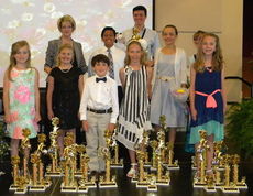 Nine students of Kay Young, top row left, stand in front of their awards won at a piano competition.
 