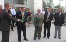 Skip Davenport cuts into the ceremonial ribbon held by George Davenport during today's ceremony at D&D Ford's new showroom and service center on Wade Hampton Blvd.