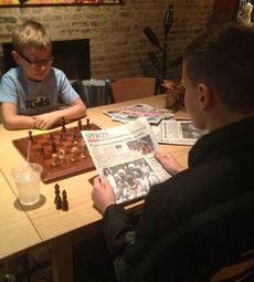 Abe Lohnes is in the midst of setting up the final moves of the chess match with Jack Ponder, who is peering over the newspaper.