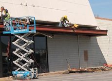 Workers are taking down the facade of the former Kmart building.