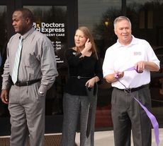 Doctors Express owner Tim Groves unrolls ribbon that was used in the ceremony Thursday.