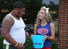 Dougie Newman makes a donation to Greer High School cheerleader Carolina Brown at the Clock Restaurant Monday evening.