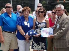 Capt. Ashley Blessums presents the United States flag, that flew over Sharana, Afghanistan, and certiicate of authentication, to John Mansure, President of Greer Memorial Hospital. To the left are her parents, Bob and Ashley Blessums.