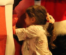 Ryann Hoffhaus, 3, peeks through the wrapping to see what big present awaits her.
 