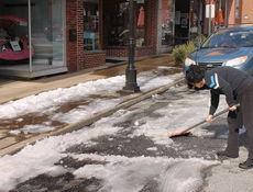Lisa Garland shovels ice from parking places in front of the Stomping Grounds on Trade Street.
 