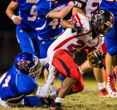 A Riverside player hangs on to Hillcrest player to make a tackle by a thread.
 
