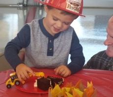 Emery Ford, 3, wearing a fire hat, figured it was easier to dive into his birthday cake with a bulldozer.
