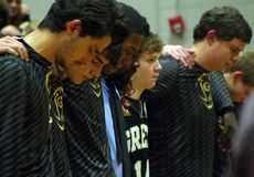 Kyle Moore, 14, is surrounded by teammates during pregame memorial.
 