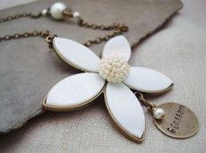 The focal point for this Flower Blossom necklace is a 2.5 inch flower made of shell and base metal with a delicate beaded center.  A charm hand stamped with 