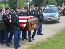 An honor guard carries the flag-draped casket of Pfc. Adam Corey Ross to his final resting place.