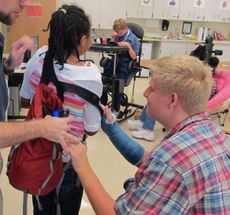 Washington Center student Daria Jenkins is assisted by classmate Jacob Ashmore preparing for a campus walk in connection with a lesson on hiking preparation.