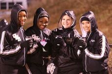 Greer cheerleaders are bundled up and enjoying a hot drink on a cold, rainy night at Dooley Field.