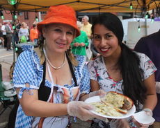 Lisa Garland, left, helps with the presentation of a bratwurst and German potato salad plate. The line can be seen wrapping behind the station.
 