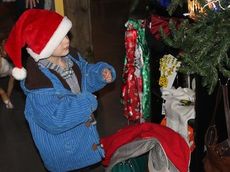 A young boy peers around the Christmas tree at Santa Claus.
 