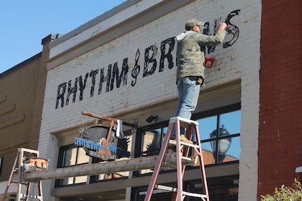 Daniel Millwood puts the finishing touches on the new Rhythm & Brews signage last Friday.