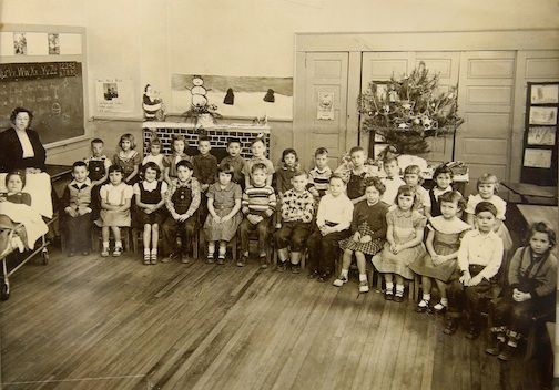 Note the class photo with the little girl on a bed in the far left. Apparently it was taken during a Christmas season celebration.
 