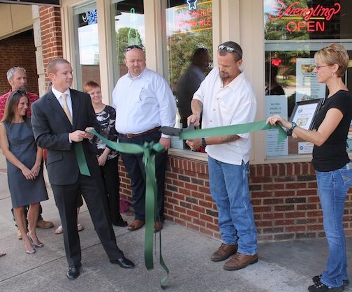 Vaughn Bragg cuts the ceremonial ribbon to mark Pour Sports Pub part of the Greer Station food and entertainment destinations. Allen Smith, Greer Chamber of Commerce President/CEO, and other downtown merchants attended.