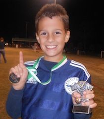 Avery Miller has a championship medal draped around his neck, a soccer trophy for a job well done and holds his finger high signaling where the Sharks finished in the 10 Under division.