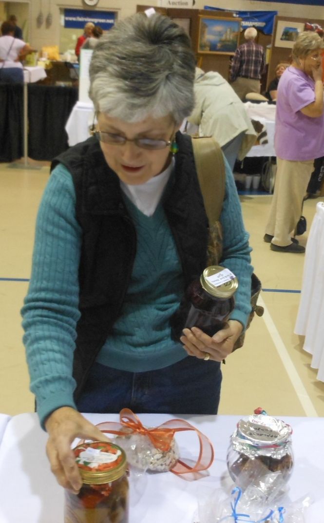 Margaret Lindsey holds a jar of pickled beets while perusing one of the tables showcasing canned foods and sweets and desserts. Most of those items were picked over earlier in the morning.
