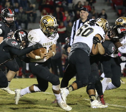 Noah Hannon (60) of Greer puts a crunching block on a Blue Ridge player, knocking his helmet backwards, as he frees more running room for Adrian McGee (24).
 