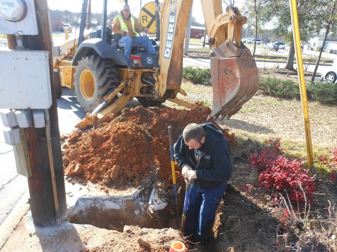Gerald Skidman, foreground, and Joe Laws, both from Triple B Boring, work at this concrete crossroads that will connect the cable to the telephone pole and run it across Poinsett Street to city hall.
