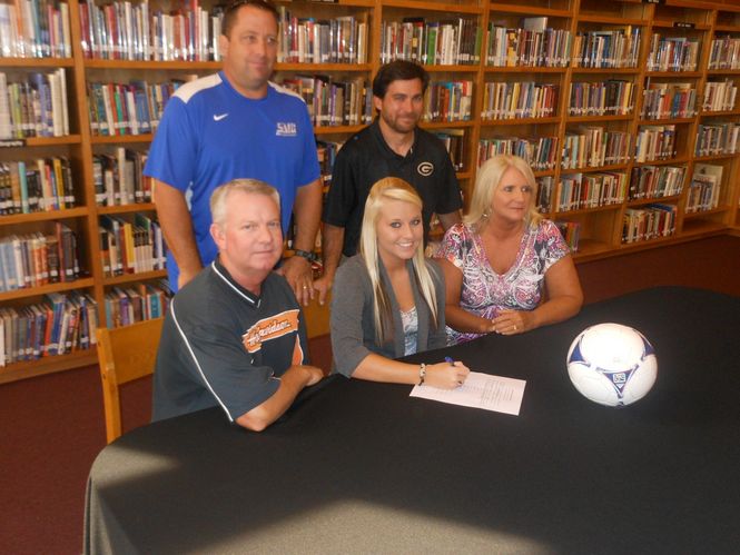 Spartanburg Methodist College girls soccer coach Dan Kenneally (blue shirt) and Greer coach Rob DePaol attend Kendal Strawhorn's signing ceremony. Her parents, Ken and Donna, attended the ceremony.