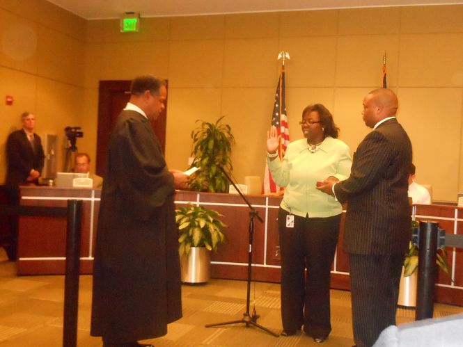 Councilwoman Kimberly Bookert, representing District 3, is sworn in for her first full term on city council. Municipal Judge Henry Mims presides. Bookert's husband, Kareem, holds the Bible.
 